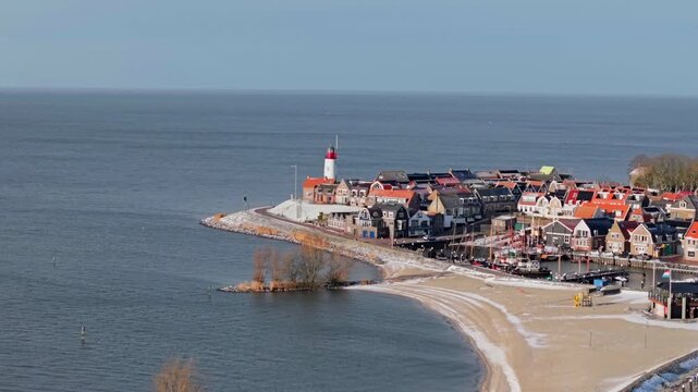 Aerial winter video of Urk harbor with lighthouse and wind turbines