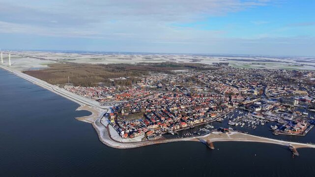 Aerial winter video of Dutch harbor town with offshore wind farm