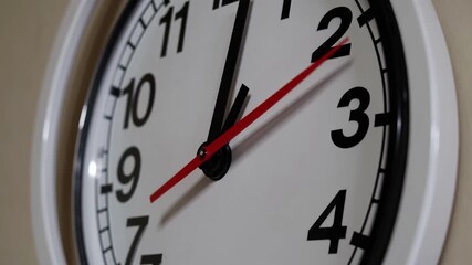 Close-up video of a wall clock at an angled perspective, emphasizing the passage of time with a focus on the clock's face and hands.