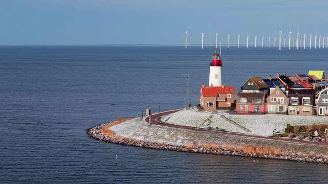 Aerial winter video of Urk harbor with lighthouse and wind turbines