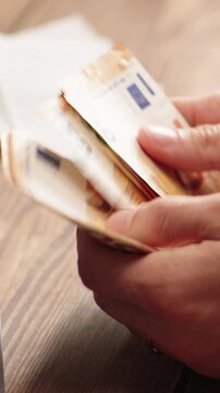 VERTICAL VIDEO: Man counting euro banknotes. Savings or investment planning concept for personal finance. Ideal for financial education content.