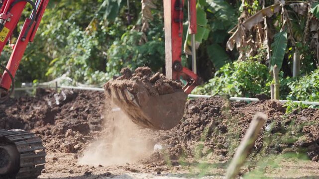 Excavator digging soil at an outdoor construction site for land preparation and infrastructure development, civil engineering work in progress.
