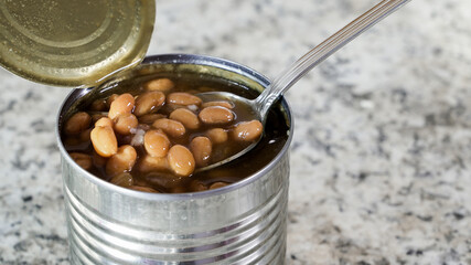 Baked beans in an open metal can with a spoon ready for serving