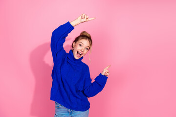 Young woman in blue knit sweater celebrating with a joyful pose against pink background