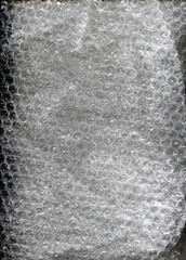 Transparent bubble wrap texture with soft reflected light. Plastic packaging material background, protective wrapping surface, abstract pattern, close up.