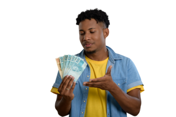 A happy young man holding Brazilian real banknotes and smiling.