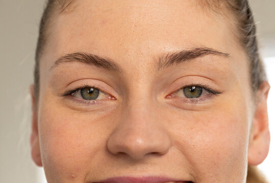 Female facing camera, making slight closed-mouth smile in room, showing skin texture and catchlight