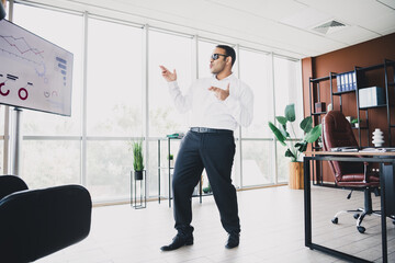 Businessman presenting in a bright loft office with charts gesturing confidently to inspire strategy and development in a professional corporate setting