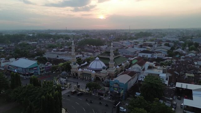 Purbalingga, Central Java Indonesia - January 2026: Aerial drone view of Masjid Agung Darussalam at sunset with city skyline and evening light, capturing peaceful Islamic architecture and urban lands