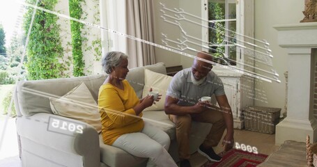 Naklejka premium Sipping couple wearing gray polo and mustard top, holding white mugs in living-room by glass doors