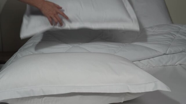 white pillows on the bed, female hands rearranging the bedclothes