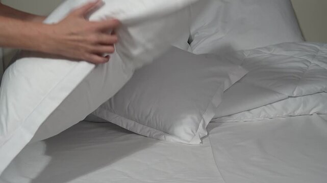 white pillows on the bed, female hands rearranging the bedclothes
