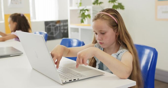 Classmates preteen girls main girl tapping white laptop in class for classwork, stretching fingers