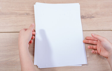 Obraz premium Hand holding sheets of paper on wooden background