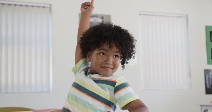 Teacher asking question African child raising right hand in classroom at desk showing readiness