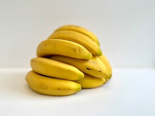 Stack of ripe yellow bananas isolated on white background, fresh tropical fruit arranged in a simple composition showing natural texture and healthy food concept.