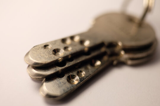 Macro shot of three brass high-security dimple keys on a white background, featuring shallow depth of field focusing on the drilled patterns and metallic texture.
