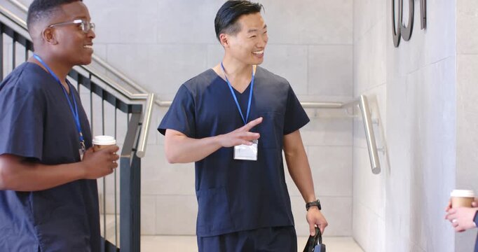 Diverse staff in scrubs holding cups and IDs, welcoming colleague entering stairwell carrying bag