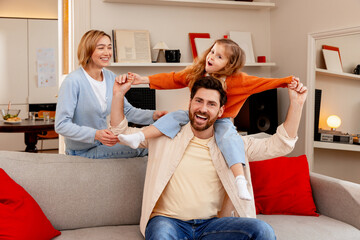 Fototapeta premium Happy family bonding in living room with parents embracing child