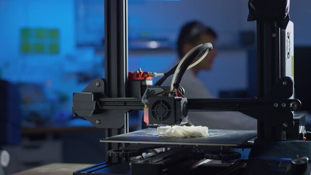 Professional engineer adjusts settings of a 3D printer while producing prototypes in a modern laboratory focusing on additive manufacturing.