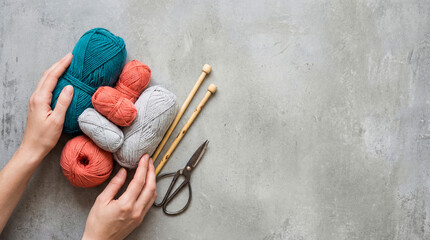 Hands prepare to knit with colorful yarn, scissors, and needles on a flat surface in a crafting space