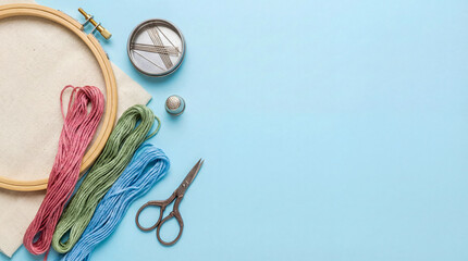 Crafting supplies are arranged on a light blue surface with colorful yarn, scissors, needles, and an embroidery hoop for a DIY project