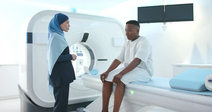 Radiology tech in hijab instructing while male patient adjusting gown and preparing CT scan