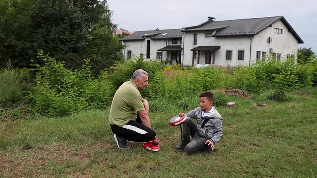 The coach squats and explains an exercise to the boy, a short pause and movement analysis during training.
