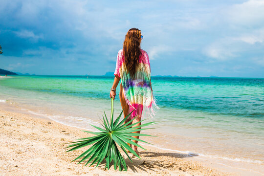 Beautiful lady in a swimsuit and colorful parasol against the background of the sea, on a tropical island, walk on the coast, sitting on a hammock, summer mood