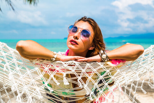 Beautiful lady in a swimsuit and colorful parasol against the background of the sea, on a tropical island, walk on the coast, sitting on a hammock, summer mood