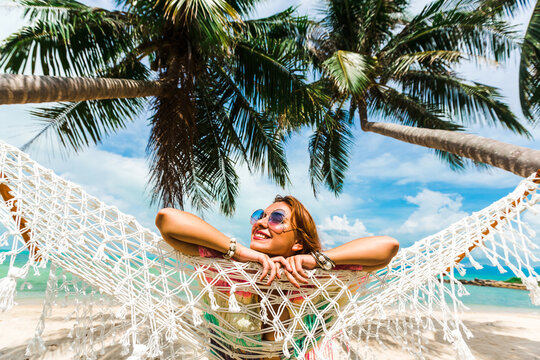 Beautiful lady in a swimsuit and colorful parasol against the background of the sea, on a tropical island, walk on the coast, sitting on a hammock, summer mood