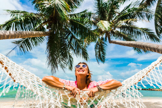 Beautiful lady in a swimsuit and colorful parasol against the background of the sea, on a tropical island, walk on the coast, sitting on a hammock, summer mood