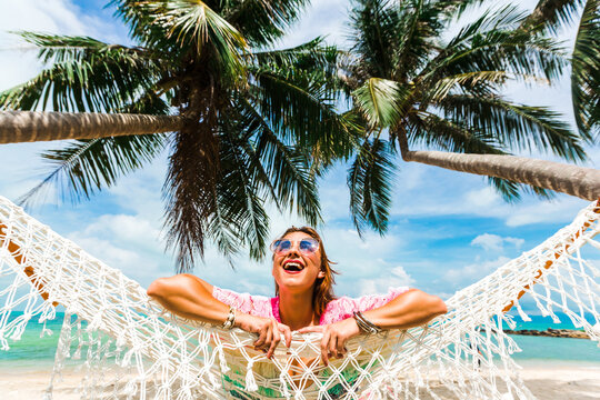 Beautiful lady in a swimsuit and colorful parasol against the background of the sea, on a tropical island, walk on the coast, sitting on a hammock, summer mood
