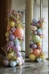 Tall bubble structures in various colors stand side by side, decorated with fresh flowers. Natural light streams through the glass, creating a festive atmosphere in the space