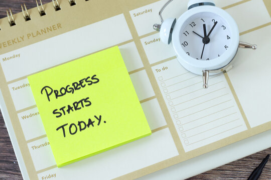 Progress starts today, inspirational quote with weekly planner and alarm clock. Time management, personal goals, business success concept. Top view.