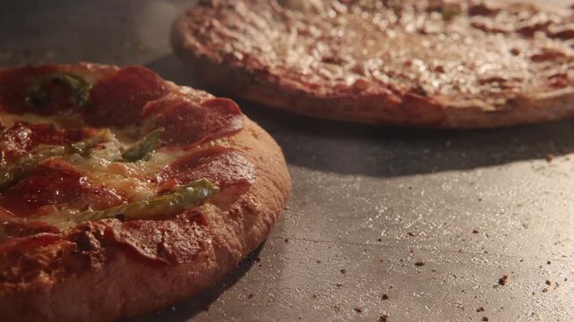 Dolly move sliding overtop overhead greasy unhealthy frozen round pizza pizzas home cooked meal for American families with big bread crusts, marinara sauce, meats, herbs, and lens flare in slow motion