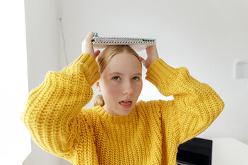 Teenage girl overwhelmed with studying, student holding notebook on head, learning difficulties, mental overload, school stress concept, home education