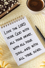 Fototapeta premium Inspirational quote to love God with all your heart in a notebook with holy bible and coffee cup. Christian obedience, wisdom, and spiritual law, biblical concept.