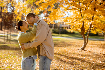Joyful couple enjoying a sunny autumn day in a park surrounded by colorful leaves