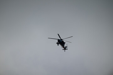 Fototapeta premium Bottom view of a modern helicopter flying alone in a gray sky. Air transport and aviation industry.