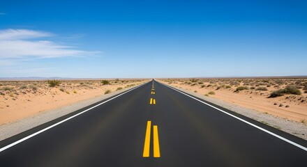 Fototapeta premium Desert highway with yellow road markings under blue sky