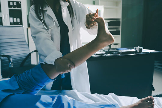 Doctor examining and supporting injured ankle of female patient in hospital room, providing medical assistance and treatment for sprain or fracture