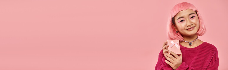 Young woman in vibrant pink attire holds a delightful gift against a soft pink backdrop