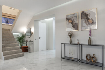A hallway features a staircase leading to another level. There are decorative items on black...