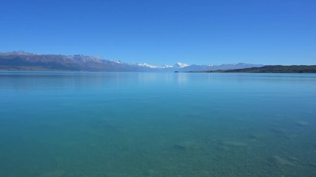 Klarer, ruhiger See vor einer fernen Bergkette unter blauem Himmel, Lake Pukaki Viewpoint, Pukaki, Canterbury, S&uuml;dinsel, Neuseeland, Ozeanien