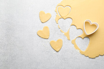 Obraz premium Uncooked heart shaped cookies, raw dough and cookie cutter on light gray table, flat lay. Space for text