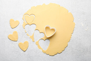Obraz premium Uncooked heart shaped cookies, raw dough and cookie cutter on light gray table, flat lay