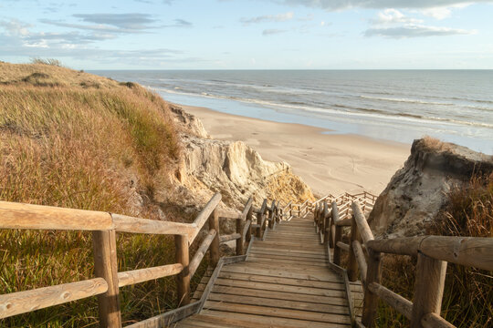 Scenic wooden stairs descending through dunes to Cuesta Maneli Beach, Huelva, Spain. Natural coastal landscape, Atlantic shoreline, travel, summer, nature and tourism concept.