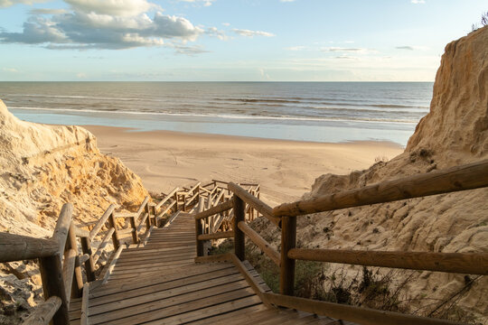 Scenic wooden stairs descending through dunes to Cuesta Maneli Beach, Huelva, Spain. Natural coastal landscape, Atlantic shoreline, travel, summer, nature and tourism concept.