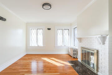 Naklejka premium Empty living room with hardwood floors, fireplace and natural window light